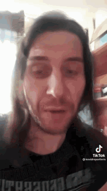 a man with long hair and a beard is wearing a black t-shirt .