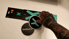 a person with a tattoo on their arm is putting a sticker on a card that says multivers