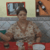 a woman is sitting at a table with a bottle of wine on the wall