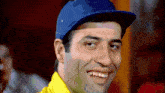 a man wearing a blue baseball cap and a yellow shirt smiles