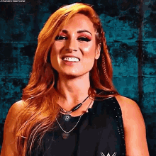 a woman with red hair is smiling and wearing a black shirt and necklace .