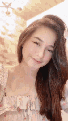 a woman in a white floral top is smiling for the camera
