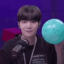 a young man is holding a balloon in front of a microphone .