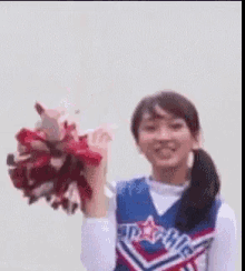 a cheerleader is holding a bunch of pom poms and smiling .