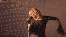 a woman singing into a microphone while holding her hair