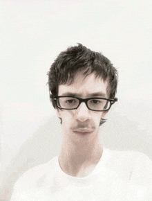 a man wearing glasses and a white shirt makes a funny face