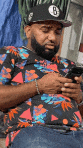 a man wearing a brooklyn nets hat looks at his phone