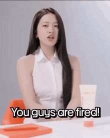 a woman sitting at a desk with the words you guys are fired behind her