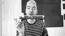 a black and white photo of a man in a striped shirt giving a thumbs up sign .