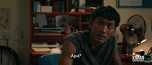 a man is sitting at a desk with a fan in front of him and says apa