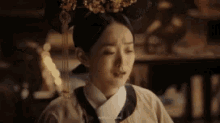 a woman in a traditional costume is sitting in a dark room with her eyes closed .