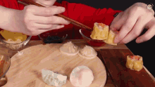 a person is eating dumplings with chopsticks on a wooden board