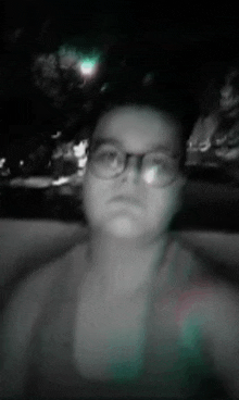 a person wearing glasses is taking a selfie in a dark room .