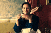 a woman sitting at a table drinking a cup of coffee