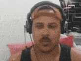 a man with a mustache is wearing headphones and a hat .