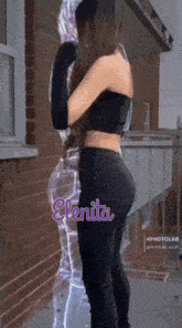 a woman standing in front of a brick wall with the name elenita on her back
