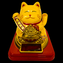 a yellow statue of a cat holding a banner with chinese writing on it
