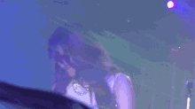 a woman in a white dress is standing in front of a blue light