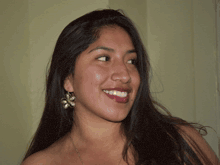 a woman with a flower shaped earring is blowing a bubble of air