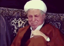 a man in a turban is sitting on a couch with his eyes closed and his tie untied .