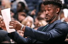 a man in a suit holds up a piece of paper