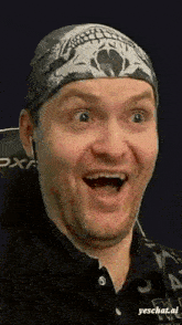 a man wearing a bandana with a skull on it is smiling with his mouth open .