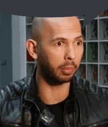 a bald man with a beard is wearing a black leather jacket and making a surprised face .