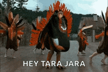 a group of people dressed as turkeys are dancing in front of a house .