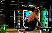 a man and woman are hugging in a room with a sign that says cw on it