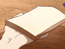 a person holding a piece of bread on a wooden table