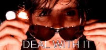 a man wearing sunglasses holds a flashlight in front of his face with the words deal with it written below him