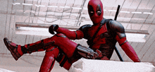 a man in a deadpool costume sits on a rock