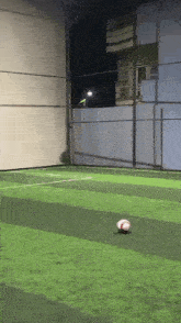 a soccer ball is on the grass on a soccer field at night .
