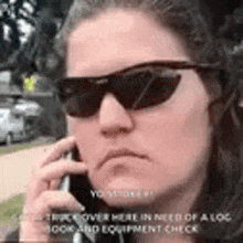 the woman is wearing sunglasses and talking on her cell phone .