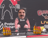 a man is lifting a barbell in front of a sign that says glam