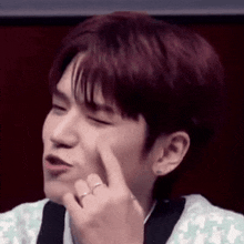 a close up of a young man making a funny face with his finger on his face .