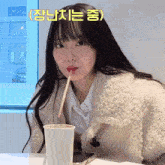 a girl drinking from a cup with a straw in her mouth with korean writing above her head