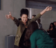 a woman with her arms outstretched stands in front of a sign that says u.s. customs and border protection