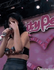 a woman singing into a microphone in front of a sign that says pretty pea