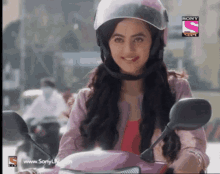 a woman wearing a helmet is sitting on a scooter with a sony logo on the bottom right