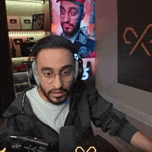 a man with glasses and headphones is sitting in front of a microphone .