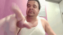 a man wearing a white tank top points at something