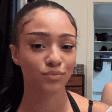 a woman in a black bra looks at the camera with a serious look on her face