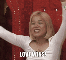 a woman with her arms in the air and the words love wins below her