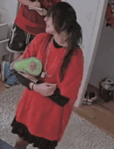 a woman in a red shirt is holding a green toy