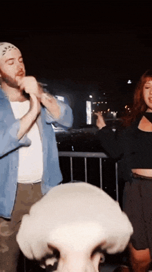 a man singing into a microphone next to a woman with red hair