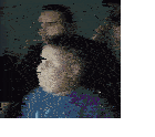 a man and a boy are sitting in a dark room . the boy is wearing a blue shirt .