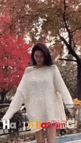 a woman in a white sweater is standing in front of a tree with the words happy lasting written on the bottom