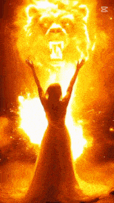 a woman in a white dress stands in front of a lion with flames coming out of it 's mouth