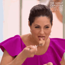 a woman in a purple dress is eating a piece of food from a fork ..
